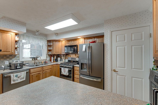 kitchen featuring decorative backsplash, stainless steel appliances, sink, and a textured ceiling