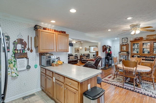 kitchen with ornamental molding, ceiling fan, a textured ceiling, and kitchen peninsula