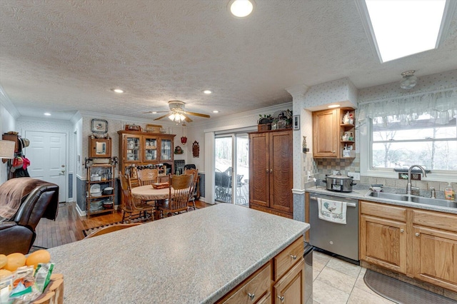 kitchen with stainless steel dishwasher, plenty of natural light, sink, and a textured ceiling