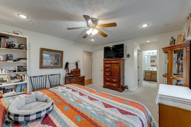 carpeted bedroom featuring ceiling fan, ensuite bath, and a textured ceiling