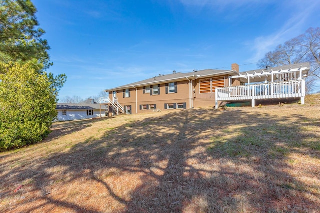 rear view of house featuring a wooden deck and a yard