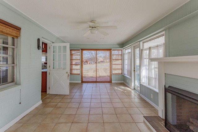 unfurnished sunroom with a brick fireplace and ceiling fan