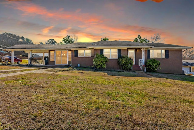 ranch-style home with a carport and a yard