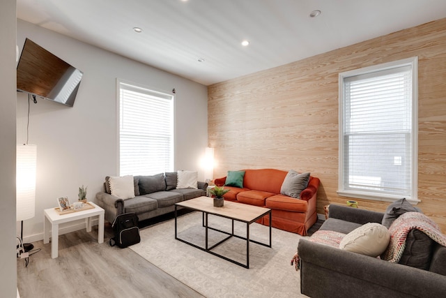 living room featuring a wealth of natural light, wood walls, and light wood-type flooring