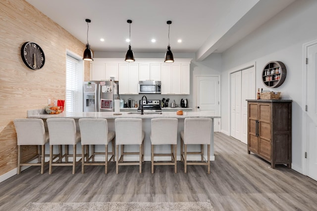 kitchen featuring stainless steel appliances, a breakfast bar area, hanging light fixtures, and white cabinets