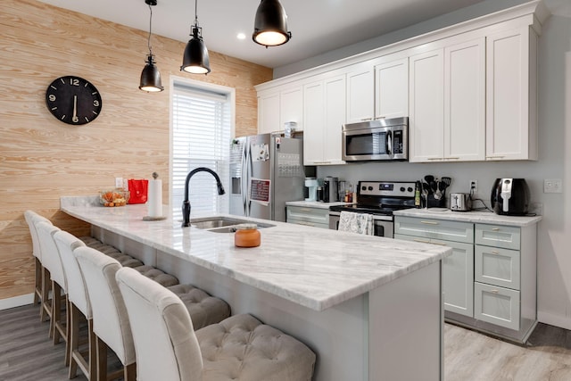 kitchen featuring pendant lighting, appliances with stainless steel finishes, a breakfast bar, and light stone counters