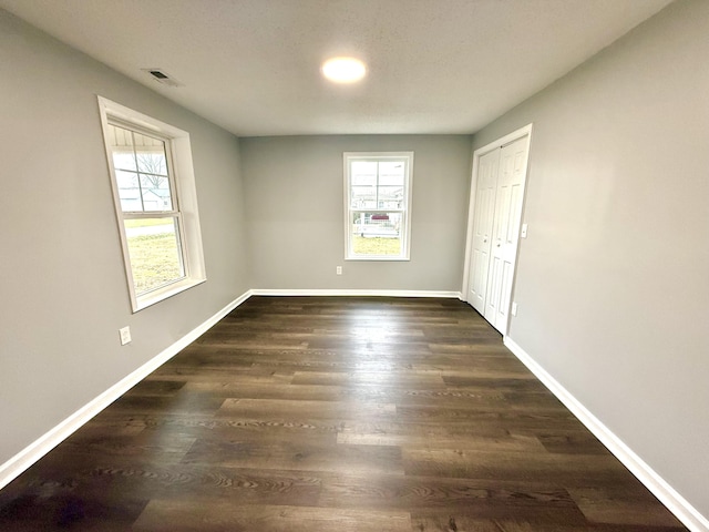 empty room featuring dark wood-type flooring and a wealth of natural light