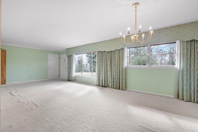 carpeted spare room with an inviting chandelier and ornamental molding