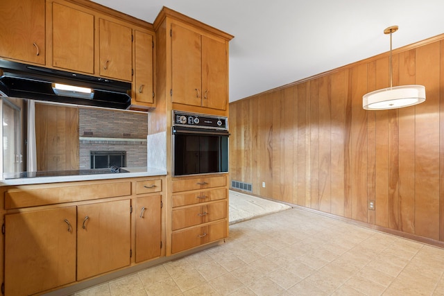 kitchen featuring pendant lighting, wooden walls, and black appliances