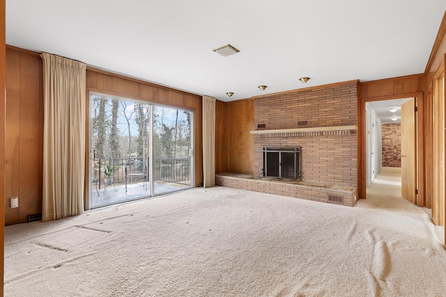 unfurnished living room with light colored carpet, a fireplace, and wood walls