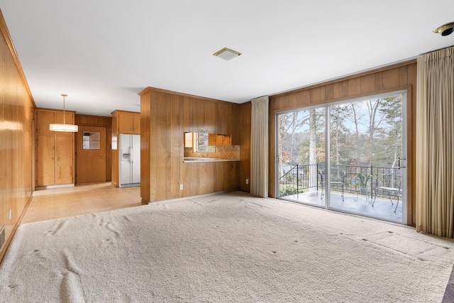 unfurnished living room with light carpet and wood walls