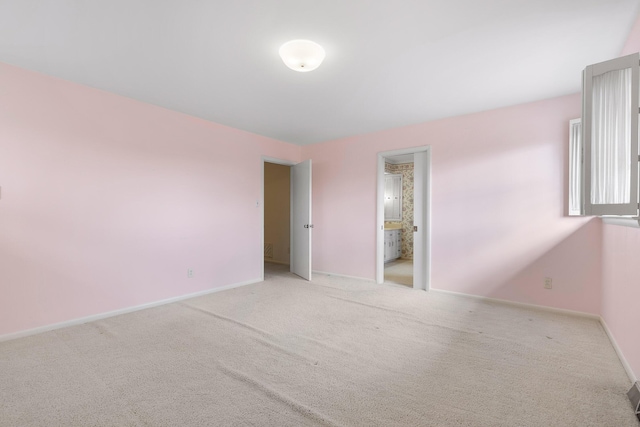 unfurnished bedroom with light colored carpet and connected bathroom