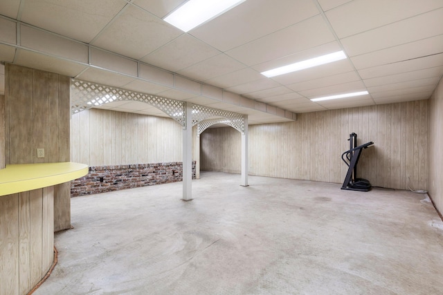 basement with wooden walls and a drop ceiling