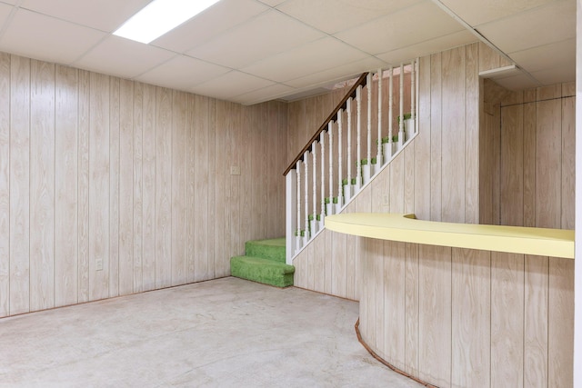 basement with a paneled ceiling and wood walls