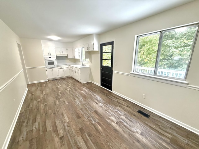 kitchen with dark hardwood / wood-style floors, white cabinetry, sink, white oven, and a healthy amount of sunlight