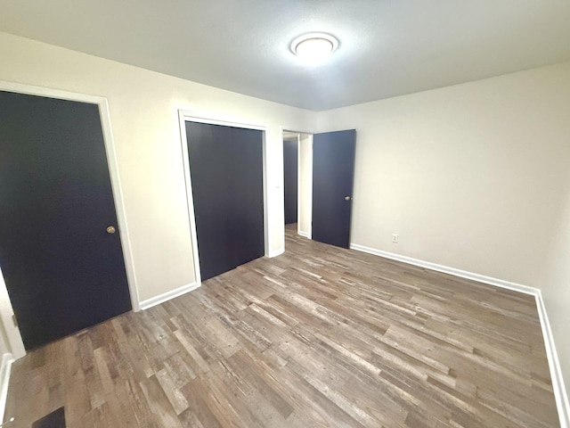 unfurnished bedroom featuring multiple closets and hardwood / wood-style floors