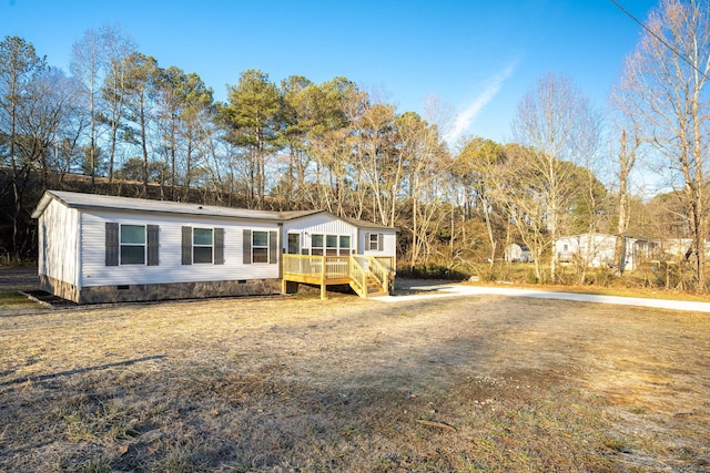 manufactured / mobile home featuring a wooden deck and a front lawn