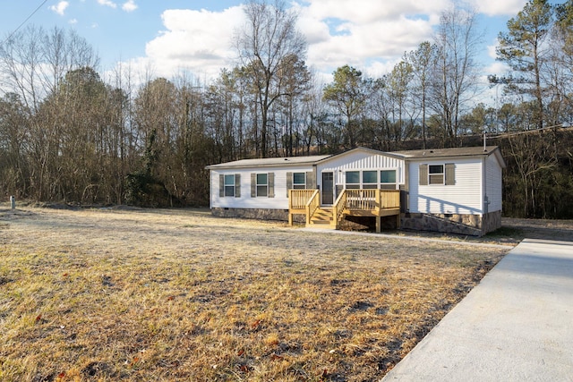 manufactured / mobile home with a wooden deck and a front yard