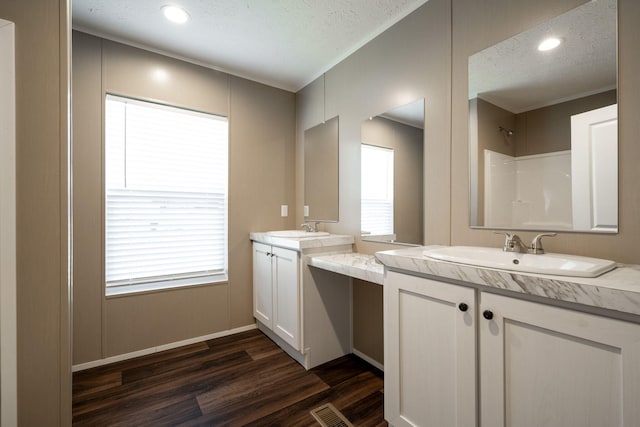 bathroom with hardwood / wood-style flooring, vanity, a healthy amount of sunlight, and a textured ceiling