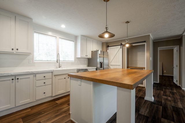 kitchen with white cabinetry, a barn door, stainless steel fridge with ice dispenser, and a kitchen island