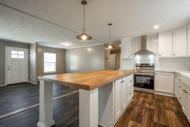 kitchen with stainless steel electric range oven, butcher block counters, white cabinets, and wall chimney exhaust hood