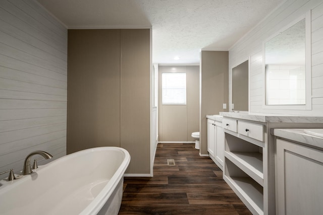 bathroom featuring a tub, hardwood / wood-style flooring, vanity, toilet, and a textured ceiling