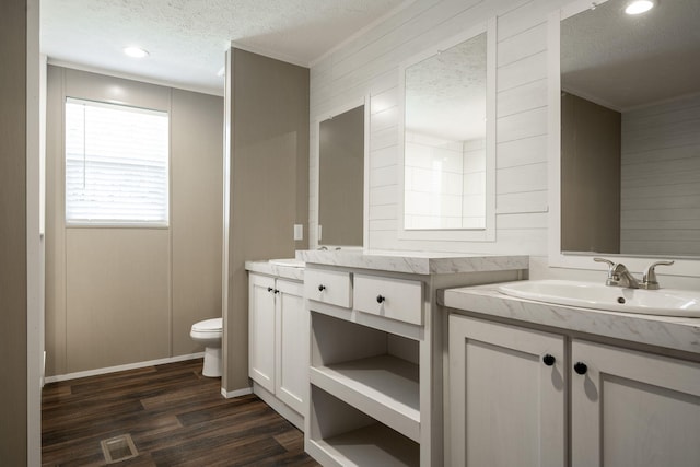 bathroom with hardwood / wood-style flooring, vanity, toilet, crown molding, and a textured ceiling