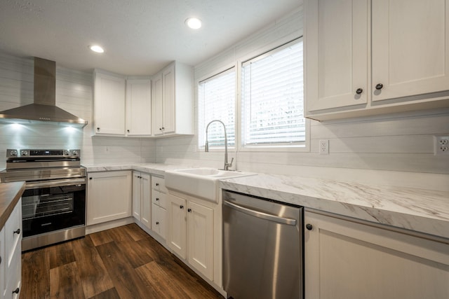 kitchen with wall chimney range hood, sink, white cabinetry, stainless steel appliances, and dark hardwood / wood-style flooring