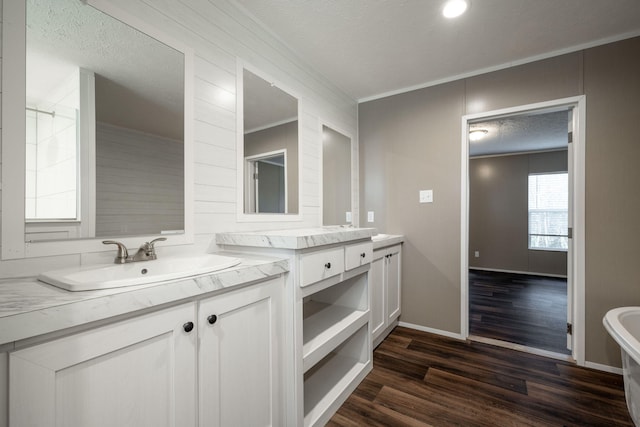 bathroom featuring hardwood / wood-style floors, a bathtub, vanity, ornamental molding, and a textured ceiling