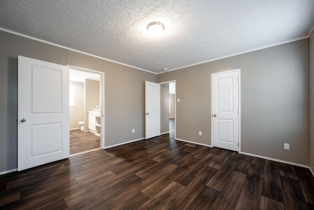 unfurnished bedroom featuring dark wood-type flooring, ornamental molding, a textured ceiling, and ensuite bathroom