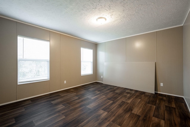 spare room featuring ornamental molding, dark hardwood / wood-style floors, and a textured ceiling