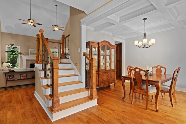 dining space with beamed ceiling, coffered ceiling, a notable chandelier, and light wood-type flooring