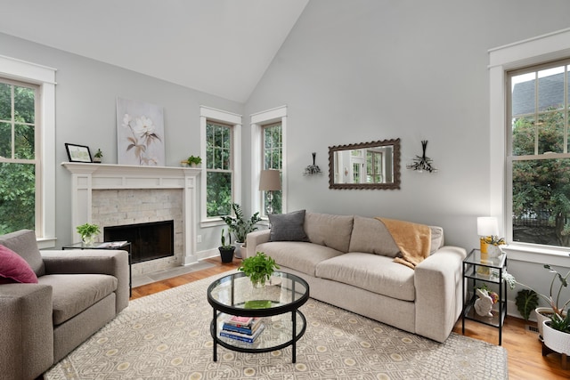 living room with a fireplace, a wealth of natural light, light hardwood / wood-style floors, and high vaulted ceiling