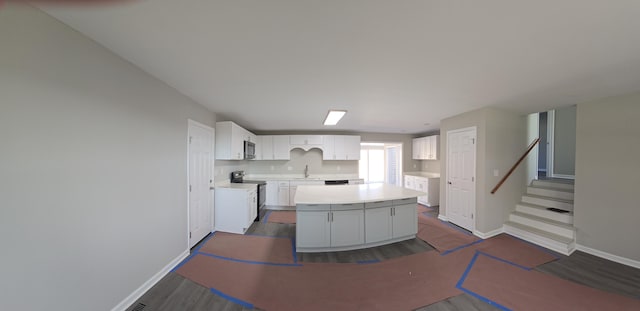 kitchen featuring white cabinetry, stainless steel electric stove, a center island, and dark wood-type flooring