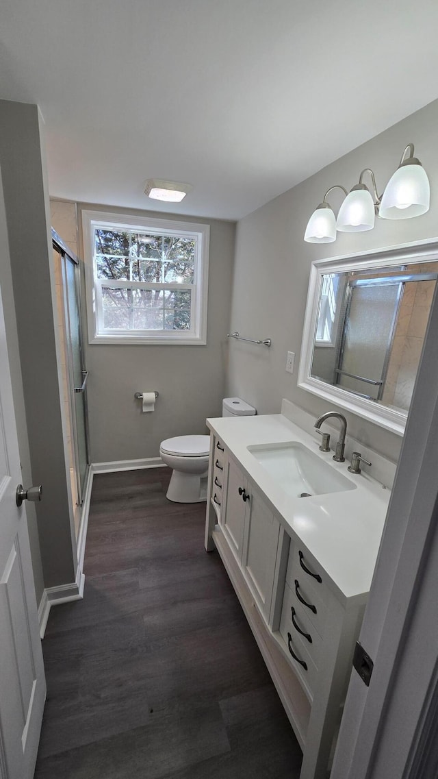 bathroom featuring hardwood / wood-style flooring, vanity, toilet, and an enclosed shower