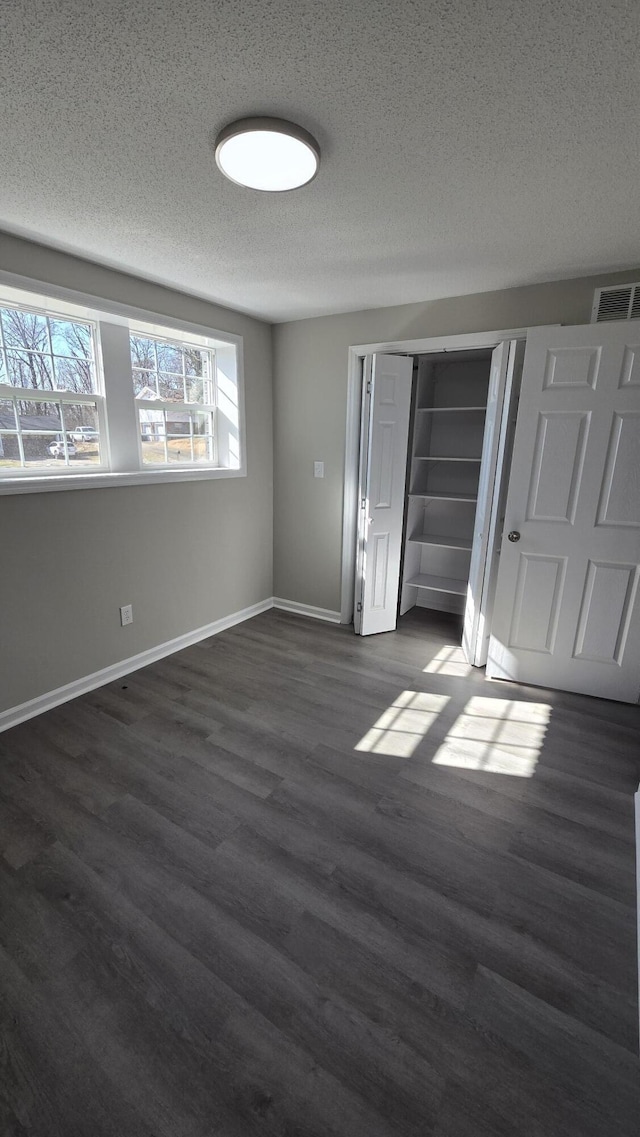 unfurnished bedroom with a closet, dark hardwood / wood-style floors, and a textured ceiling