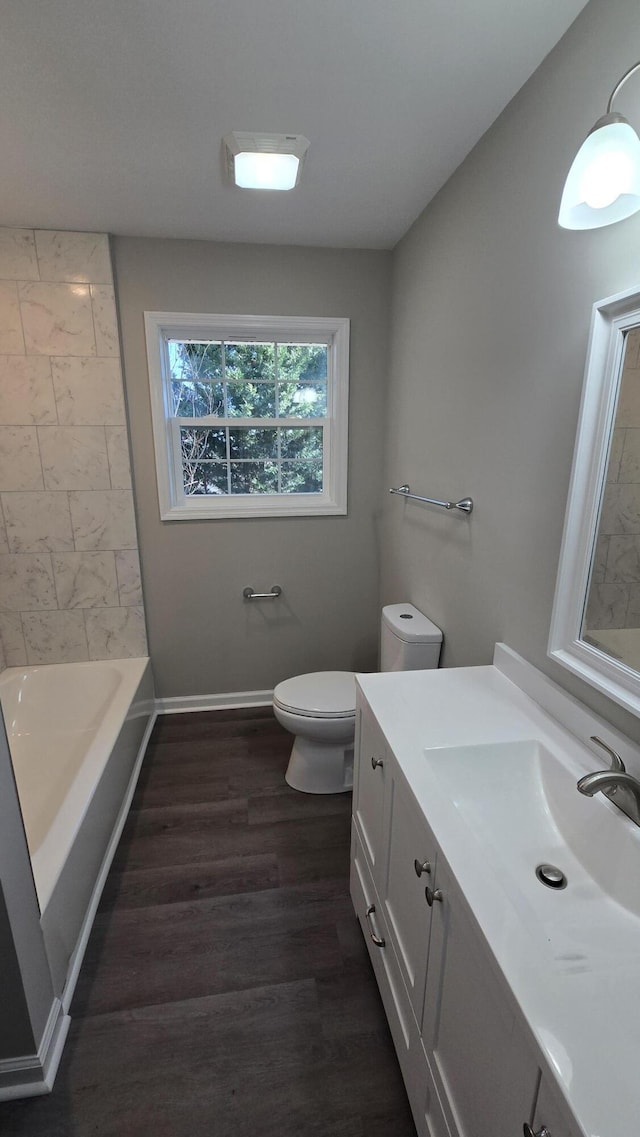 full bathroom featuring hardwood / wood-style flooring, vanity, tiled shower / bath combo, and toilet