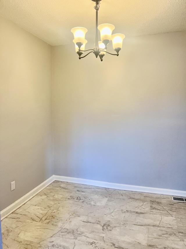 unfurnished room with a textured ceiling and a notable chandelier