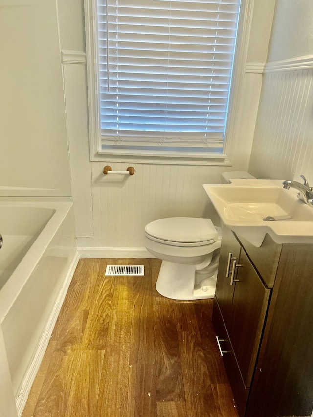 bathroom with wood-type flooring, vanity, a bathtub, and toilet