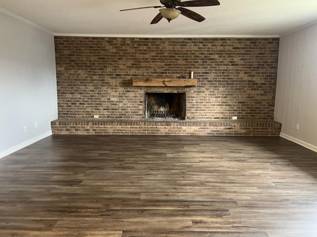 unfurnished living room featuring crown molding, a brick fireplace, dark hardwood / wood-style floors, ceiling fan, and brick wall