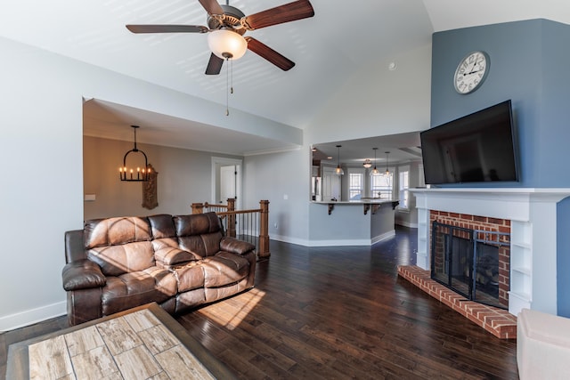 living room featuring dark hardwood / wood-style flooring, a brick fireplace, ceiling fan with notable chandelier, and high vaulted ceiling