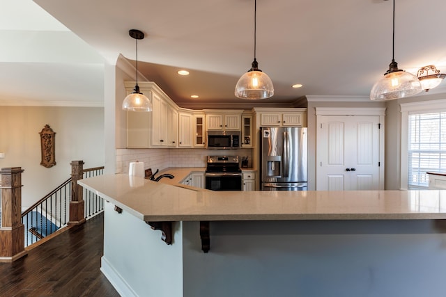 kitchen featuring stainless steel appliances, kitchen peninsula, a kitchen bar, and decorative light fixtures