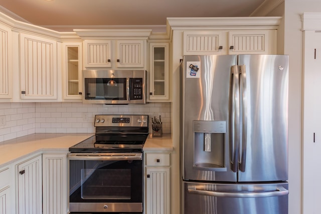 kitchen featuring tasteful backsplash, cream cabinets, and stainless steel appliances