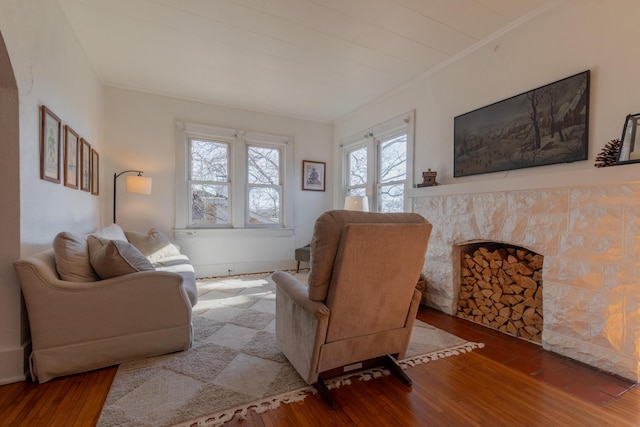 living room featuring hardwood / wood-style flooring, ornamental molding, and a fireplace