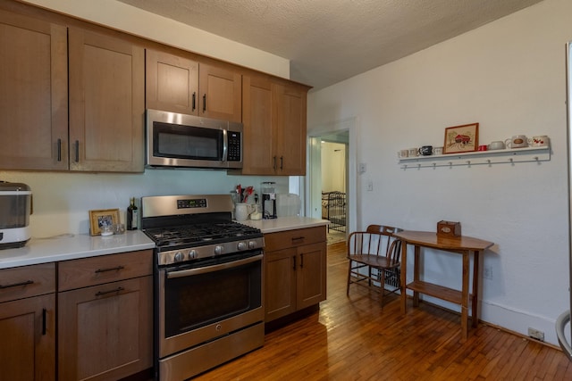 kitchen with appliances with stainless steel finishes, dark hardwood / wood-style floors, and a textured ceiling