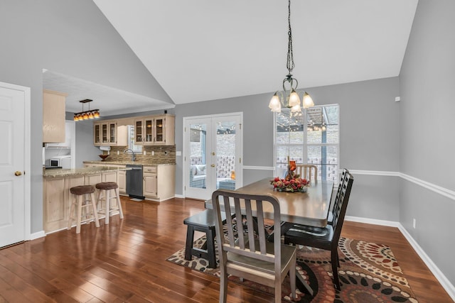 dining space with a chandelier, sink, lofted ceiling, dark wood-type flooring, and french doors