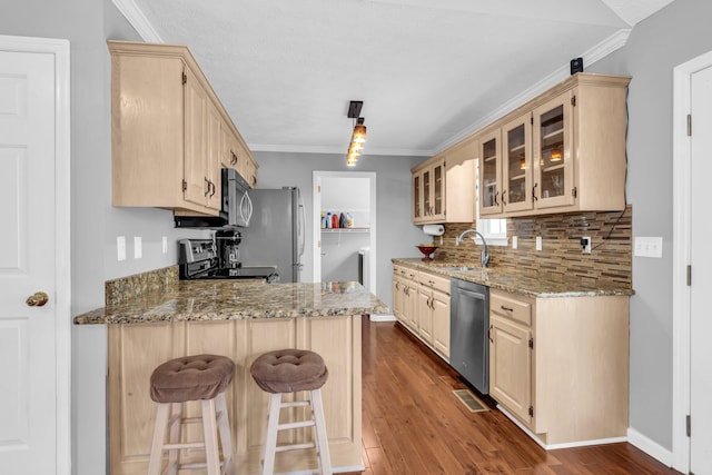 kitchen featuring hardwood / wood-style flooring, stainless steel appliances, a kitchen breakfast bar, and light stone counters