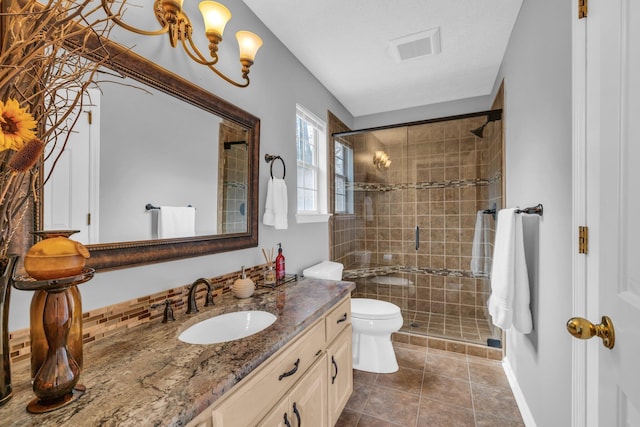 bathroom with tile patterned floors, toilet, backsplash, vanity, and walk in shower