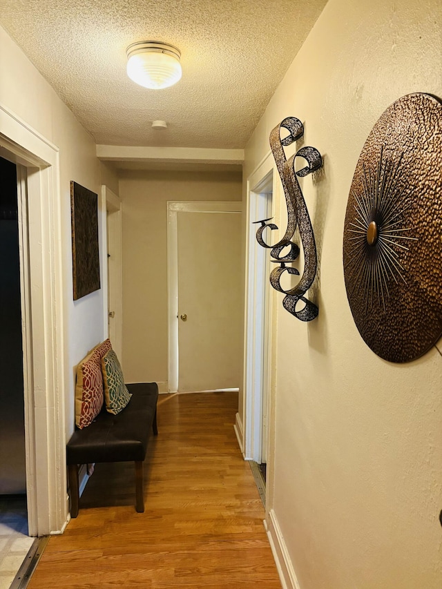 corridor with hardwood / wood-style flooring and a textured ceiling