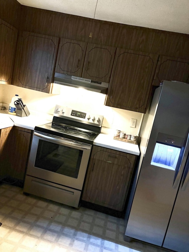 kitchen with appliances with stainless steel finishes, a textured ceiling, and dark brown cabinetry